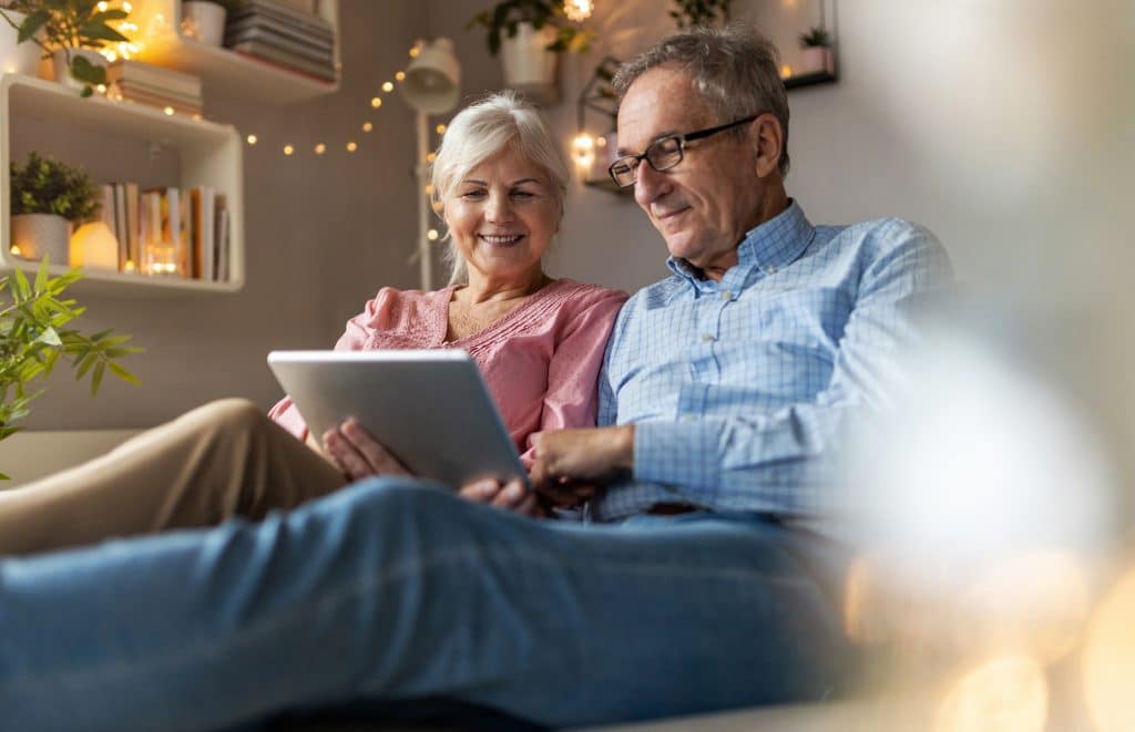 Mature couple using a laptop while relaxing at home Comparing the best Equity Release companies available on a laptop