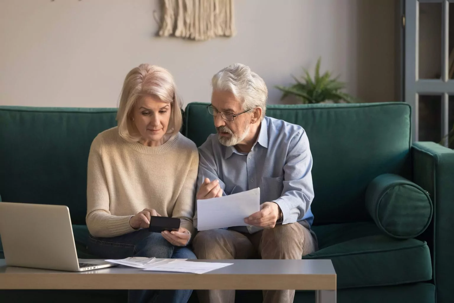 An elderly couple discussing the best lifetime mortgage rates with paperwork and figures
